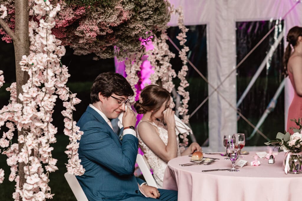 Bride and groom wiping away tears during wedding speeches at a Phipps Botanical Gardens reception
