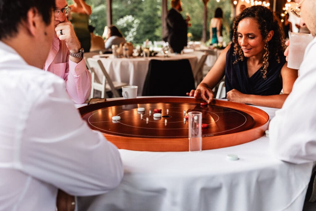 Guests playing crokinole on table with white tablecloths at Succop Nature Park wedding