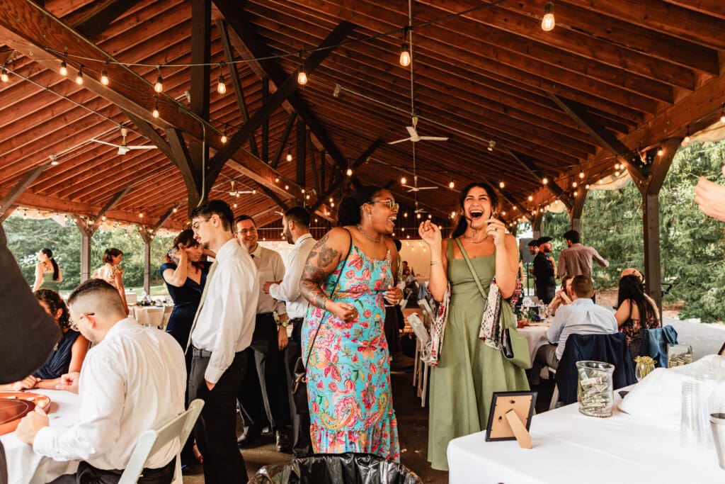 Wedding guests gathered under rustic wooden pavilion decorated with string lights at Succop Nature Park