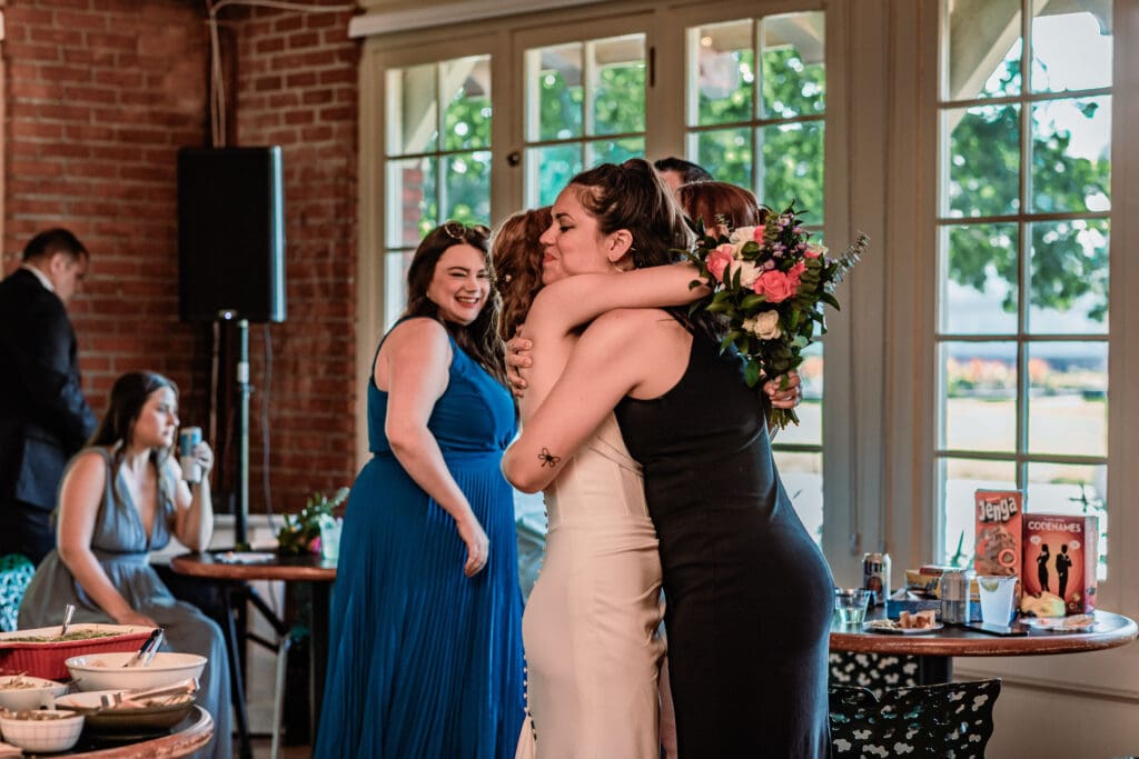 Bride hugging a friend during her Schenley Park Welcome Center wedding reception