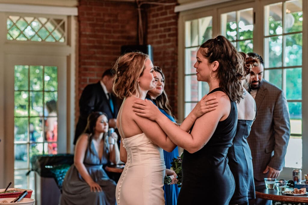 Bride chatting with a close friend at her Schenley Park Welcome Center wedding in Oakland, PA