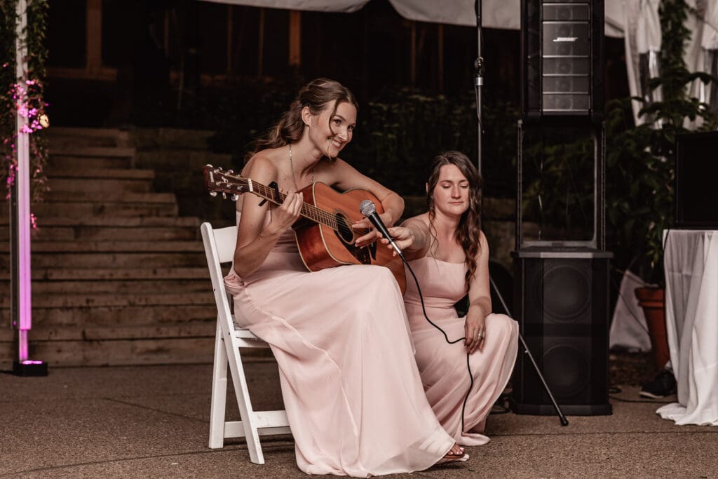 Bridesmaid performing a live song on guitar during the bride and groom’s wedding reception at Phipps Botanical Gardens in Pittsburgh