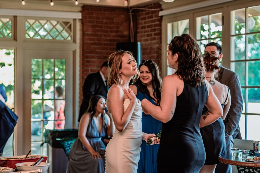 Bride sharing a candid conversation with a friend during her Schenley Park Welcome Center wedding reception