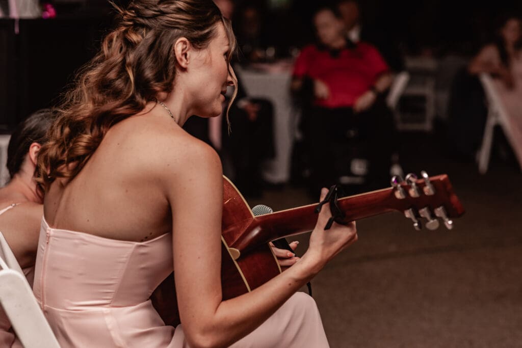 Bridesmaid playing guitar and singing during a Pittsburgh Phipps Botanical Gardens wedding reception
