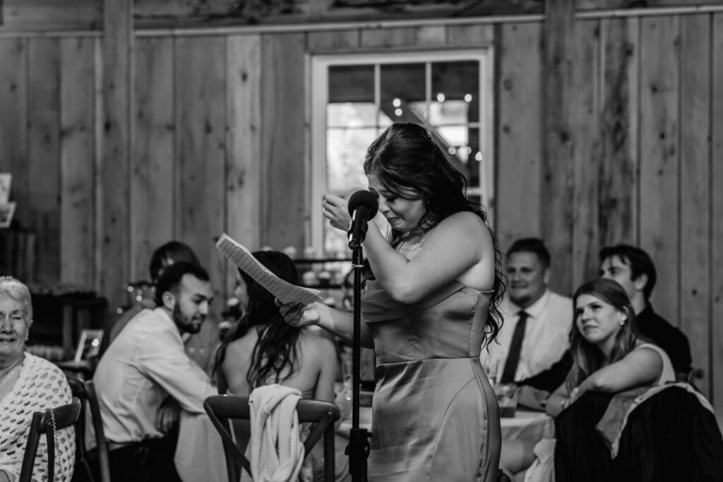 Black and white photo of emotional bridesmaid giving heartfelt speech at Hinckston Run Farm wedding reception