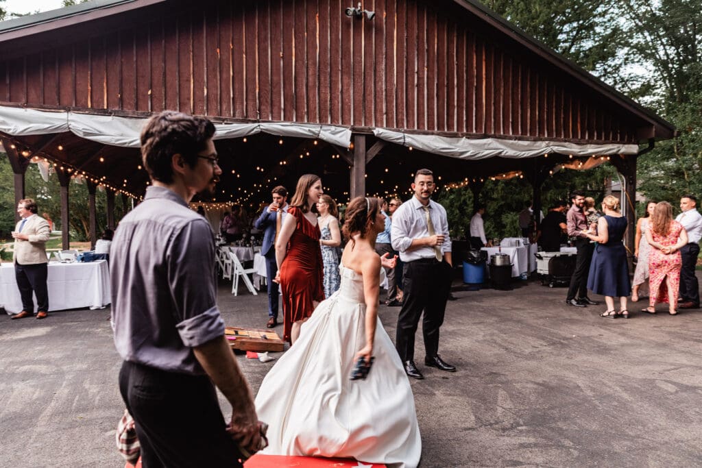Bride and wedding guests playing cornhole at outdoor reception at Succop Nature Park