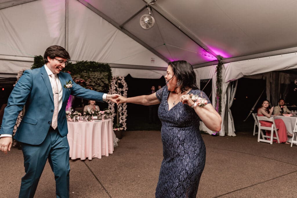 Groom dancing and smiling with his mother during the mother-son dance at a Phipps Botanical Gardens wedding reception