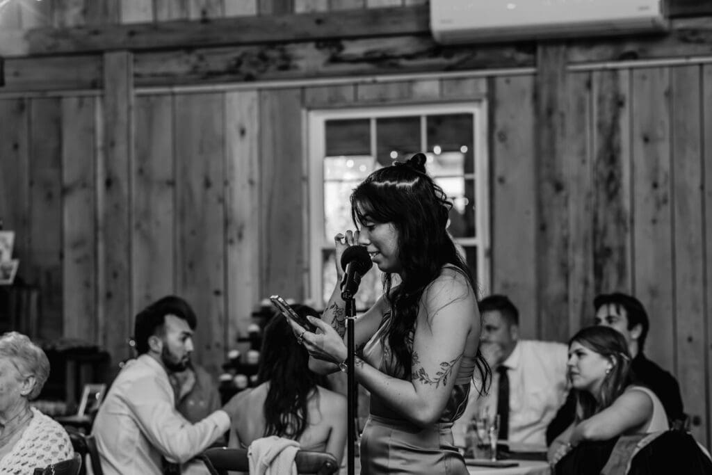 Black and white image of bridesmaid delivering emotional wedding toast at Hinckston Run Farm