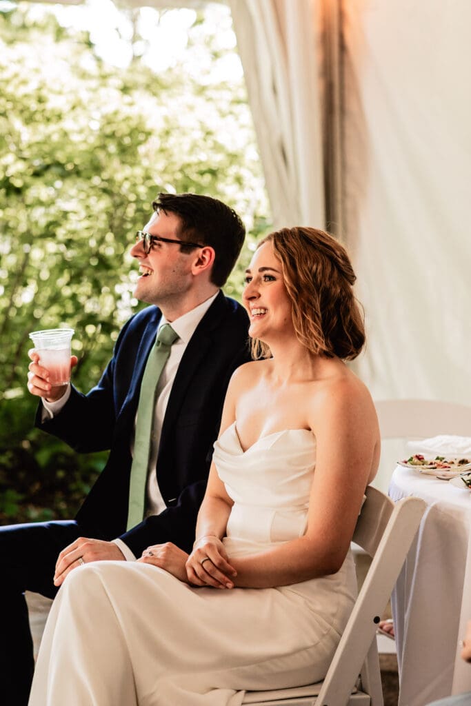 Bride and groom smiling and reacting during reception toasts at their Schenley Park Welcome Center microwedding