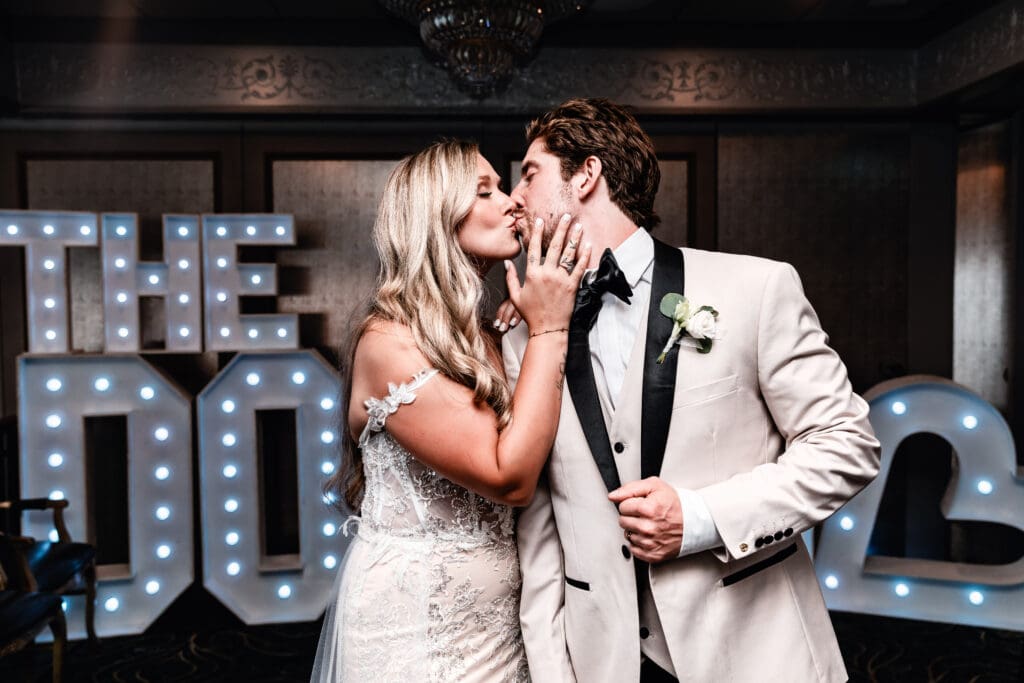 Wedding couple kissing in front of personalized marquee letters at Le Mont