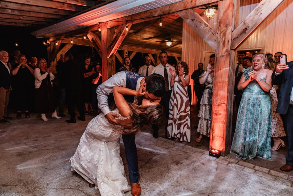 Groom dips and kisses bride during reception at Hinckston Run Farm