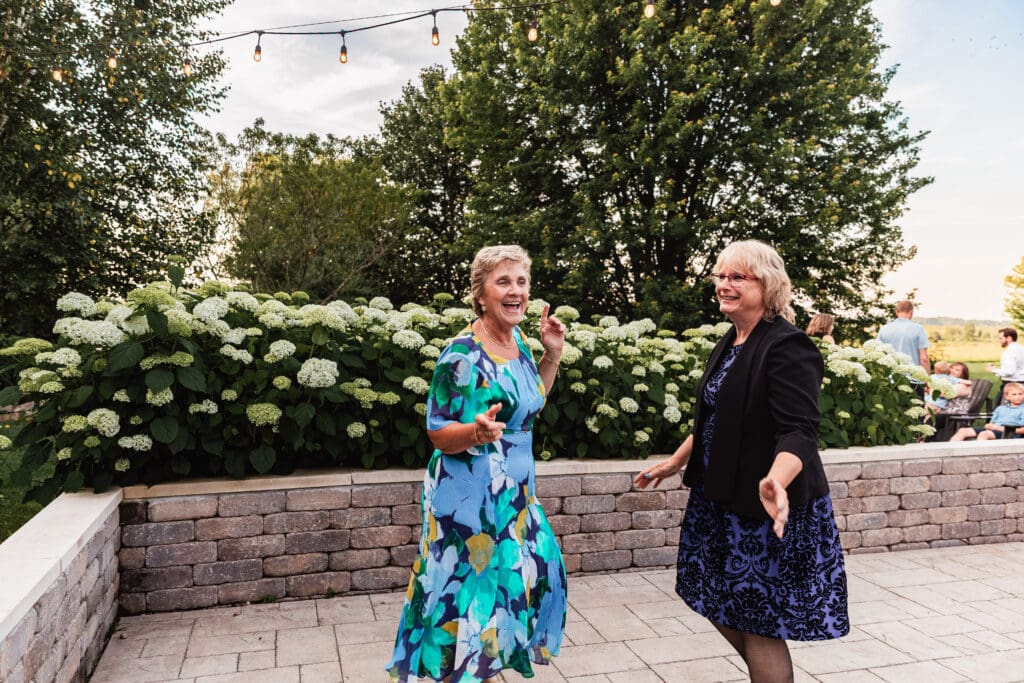 Guests laugh and dance under string lights at dusk during a Willowbrook wedding