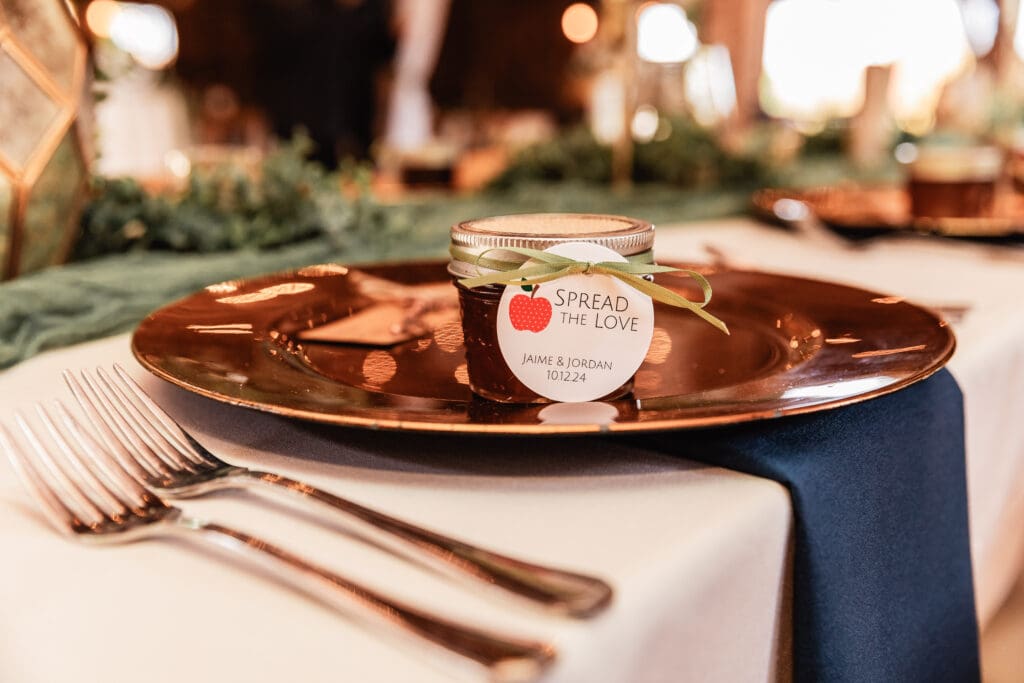 Close-up of homemade jam favor on gold charger at Pinehall at Eisler Farm wedding reception