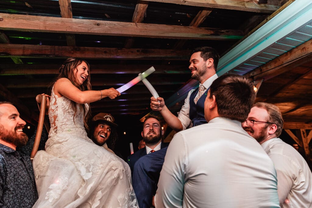 Guests lift newlyweds on chairs during celebration at Hinckston Run Farm