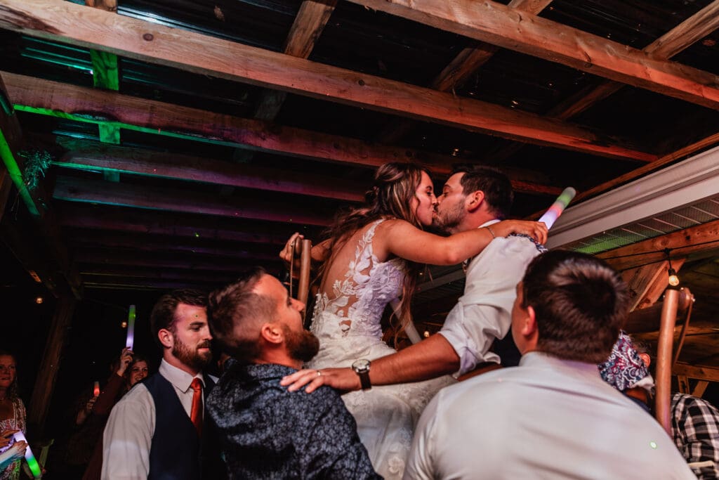 Wedding couple lifted on chairs during joyful reception at Hinckston Run Farm