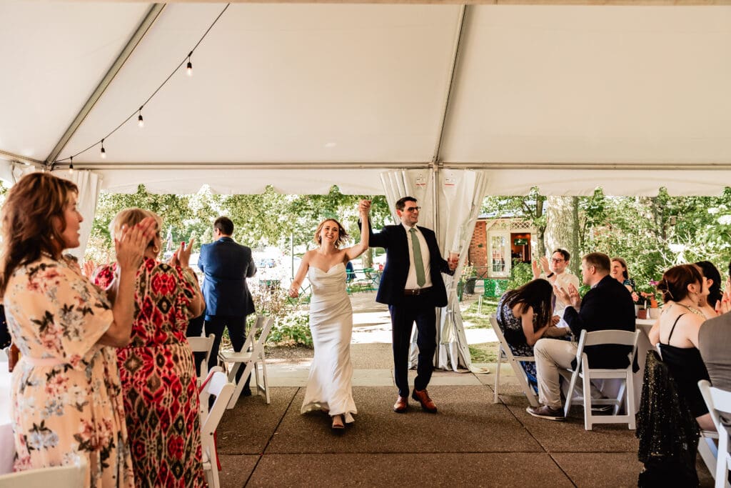 Bride and groom celebrating their grand entrance at a Schenley Park Welcome Center microwedding reception in Oakland