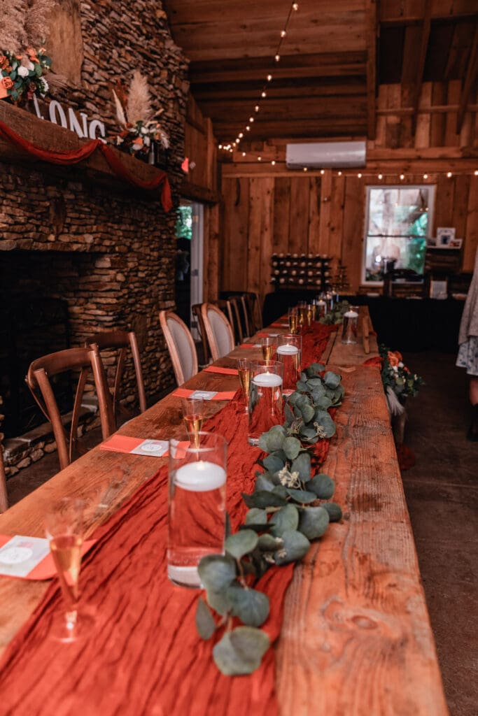 Rustic wooden dining table decorated with eucalyptus garland and candles at Hinckston Run Farm wedding