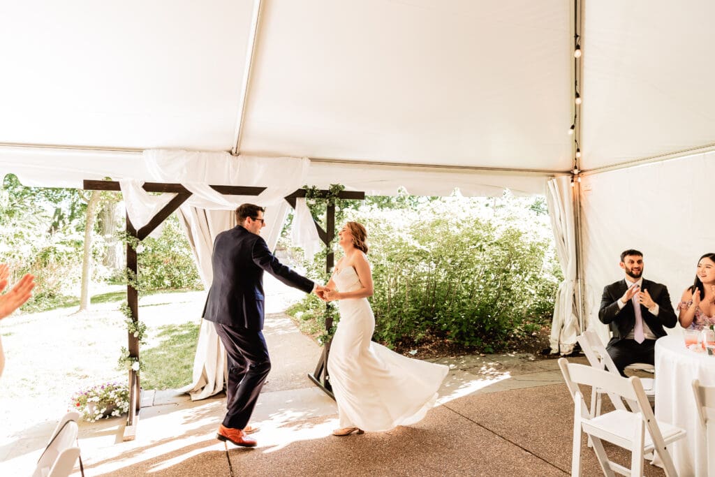Bride and groom smiling and celebrating as they make their grand entrance at Schenley Park Welcome Center reception