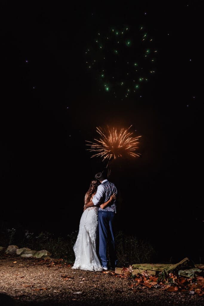 Wedding couple embraces while fireworks explode overhead at Hinckston Run Farm