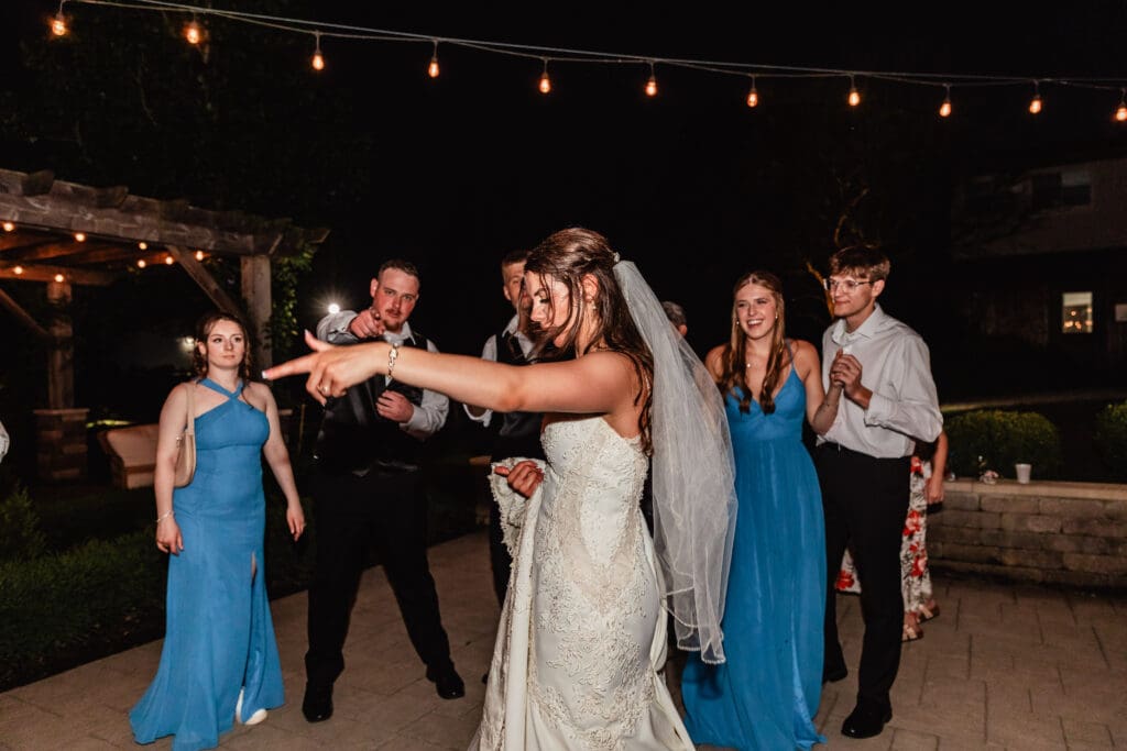 Guests laugh and dance under string lights at dusk during a Willowbrook wedding