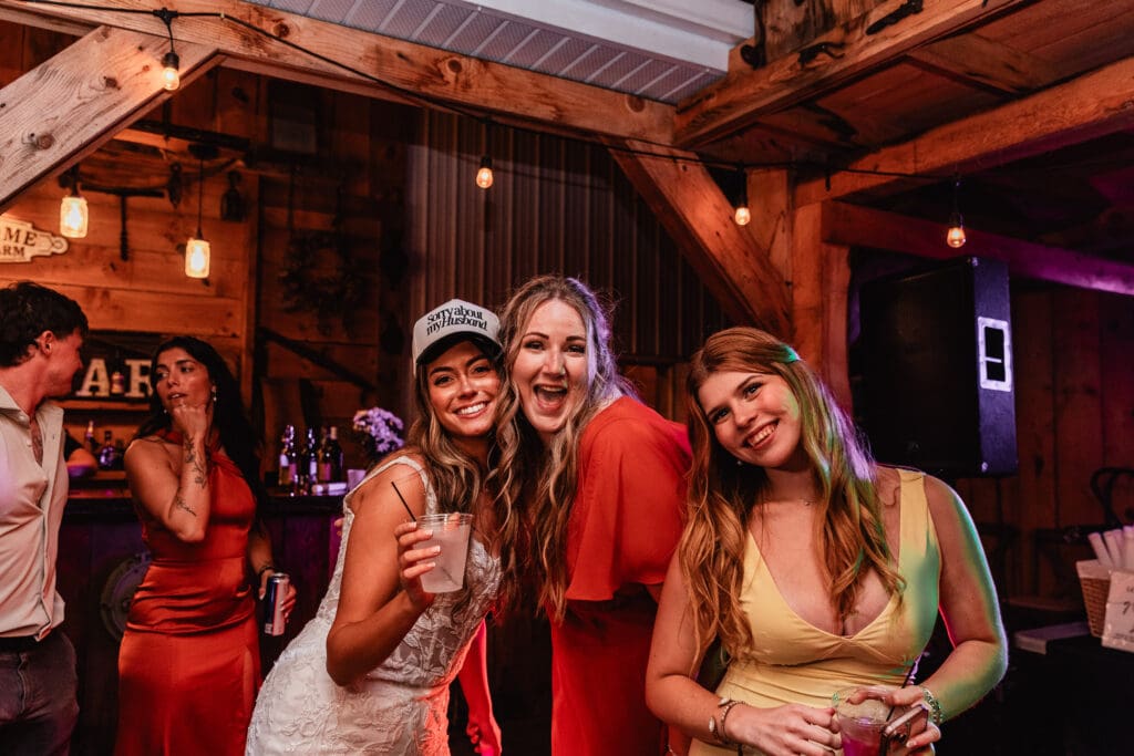 Group of wedding guests dancing under string lights at rustic barn reception at Hinckston Run Farm