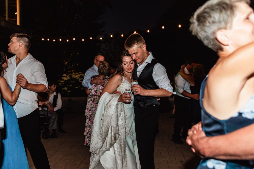 Newlyweds share an evening first dance under string lights at a Willowbrook wedding reception