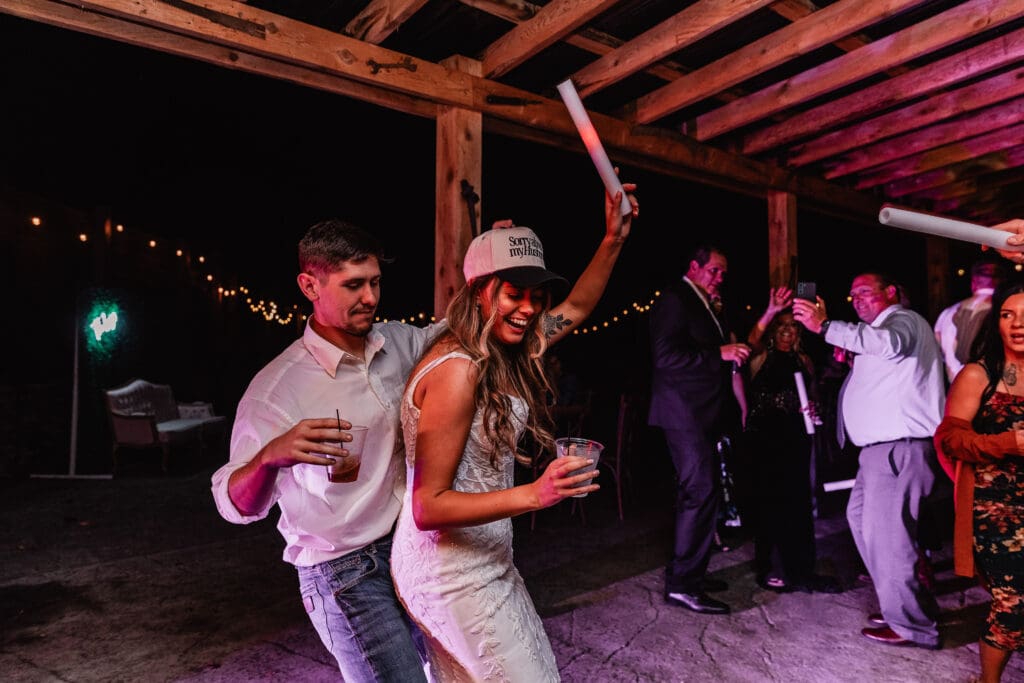 Wedding guests dancing on a dark dance floor illuminated by purple lighting at Hinckston Run Farm
