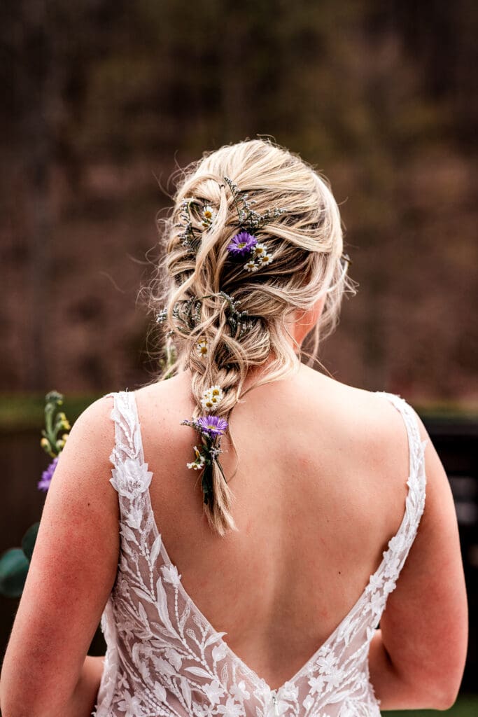 Bridal hairstyle with purple flowers woven into braid at The Fez