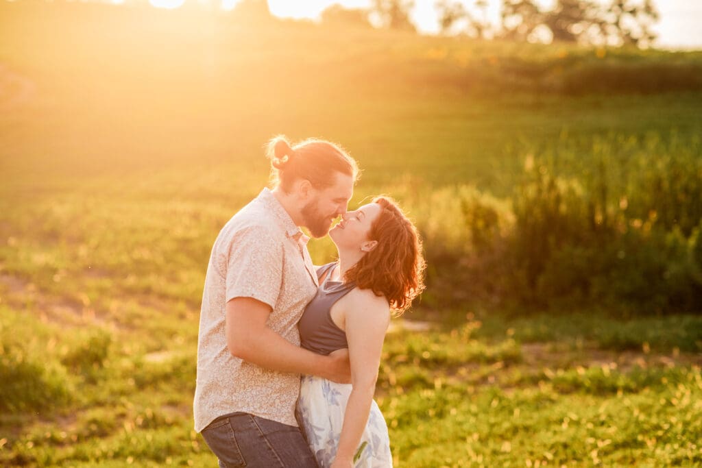 Romantic couple embracing in sunlit meadow with sunflowers during golden hour at Schwirian Sunflower Festival