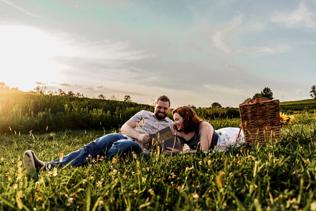 Romantic countryside picnic setup with wicker basket and engaged couple relaxing in meadow at sunset at Schwirian Sunflower Festival