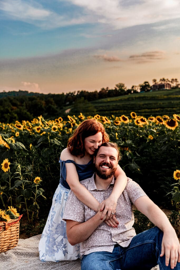 Couple laughing together at golden hour in blooming sunflower field during engagement session at Schwirian Sunflower Festival