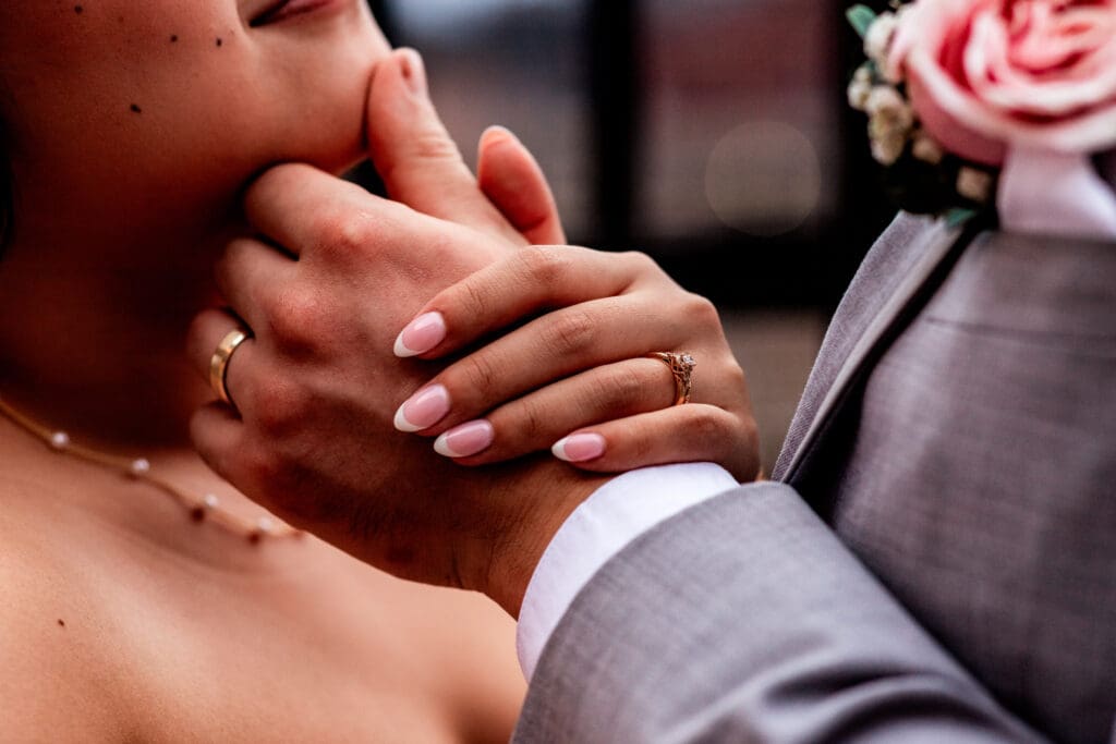 Close up of clasped hands with wedding ring and pink roses during Sheraton Station Square ceremony