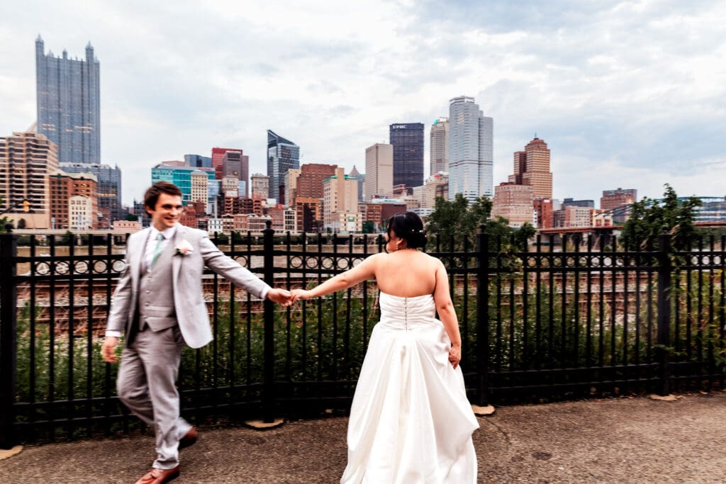 Wedding couple holds hands overlooking the Pittsburgh skyline at Sheraton Station Square