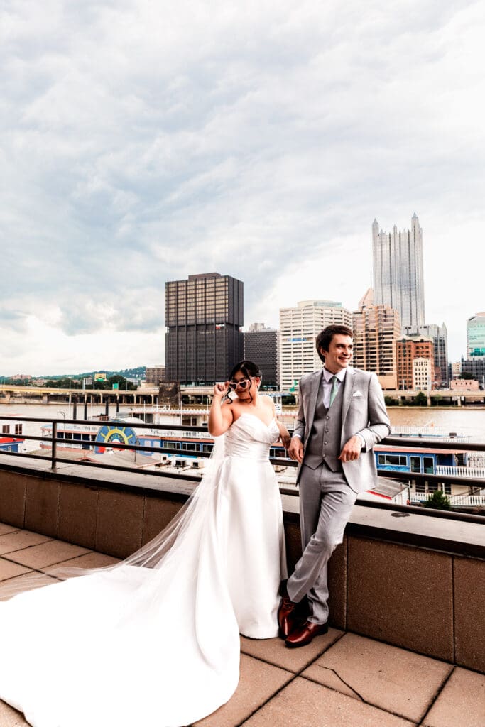 Wedding couple poses on rooftop terrace with Pittsburgh skyline at Sheraton Station Square