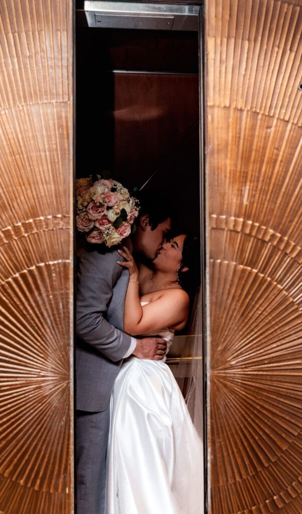 Wedding couple kisses as elevator doors close at Sheraton Station Square