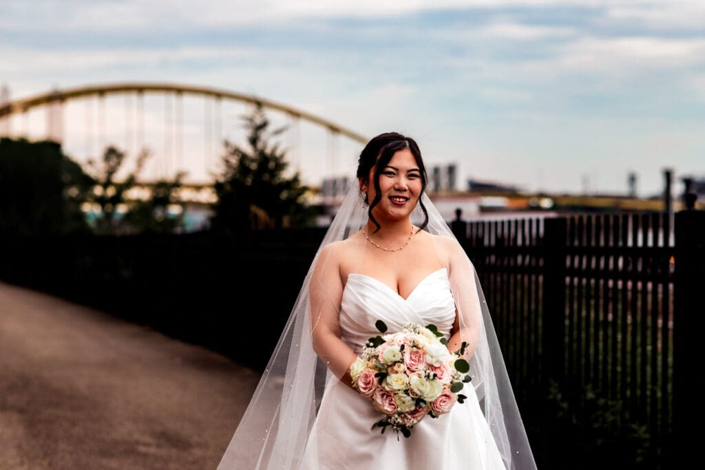 Bride in a flowing white gown poses along a path near Sheraton Station Square