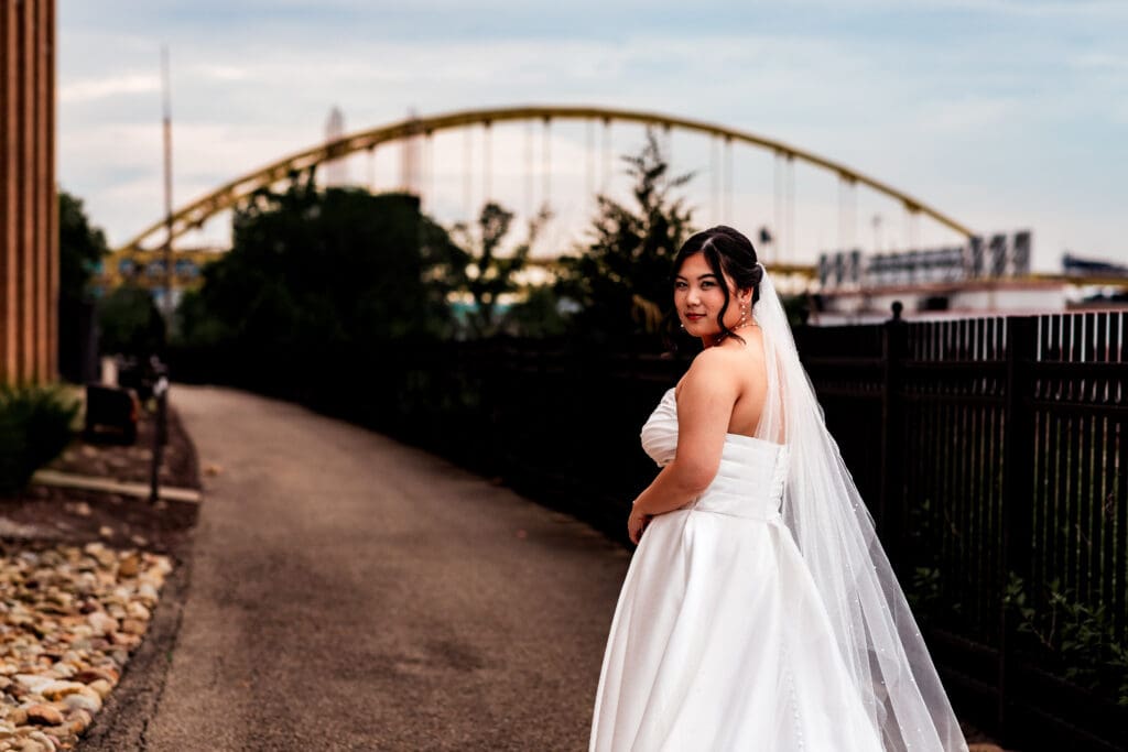 Bride stands confidently on a path during her Sheraton Station Square wedding portraits