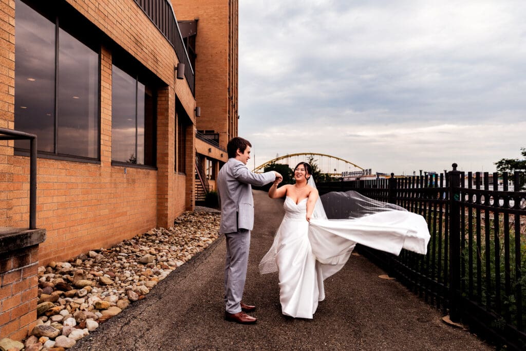 Groom spins bride as her dress billows during Sheraton Station Square wedding portraits