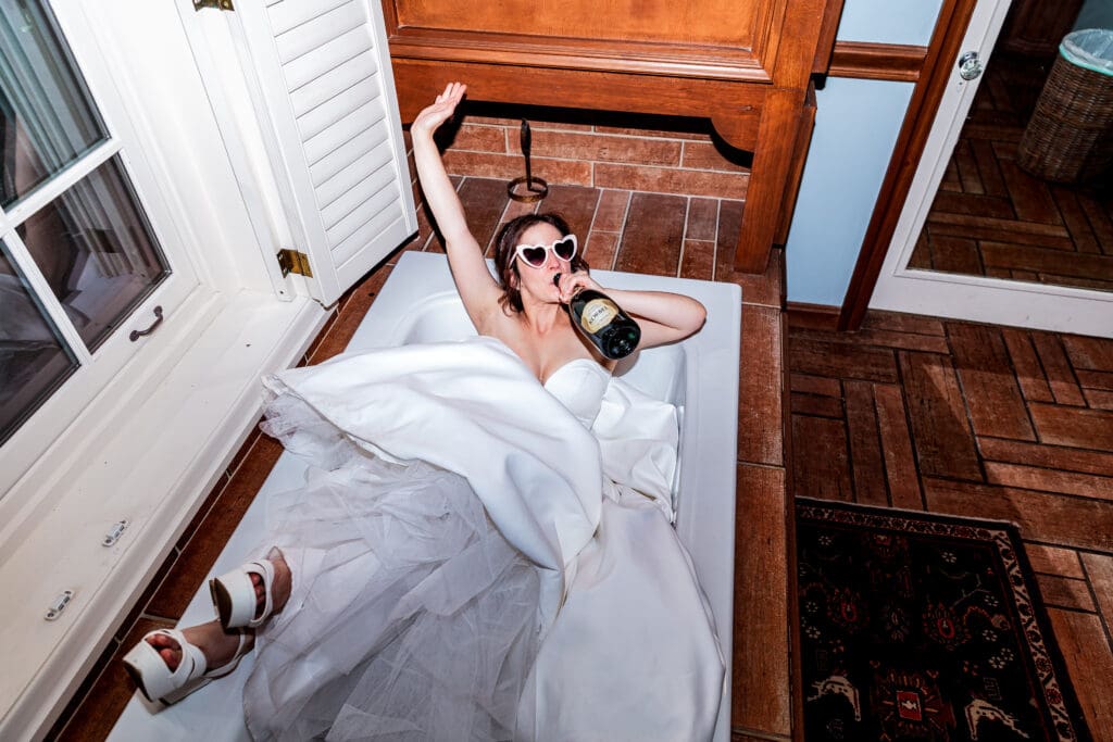 Bride in wedding dress enjoying champagne in a tub during wedding at Succop Nature Park