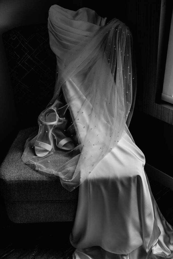 White wedding dress with veil arranged against dark background during National Aviary bridal preparation