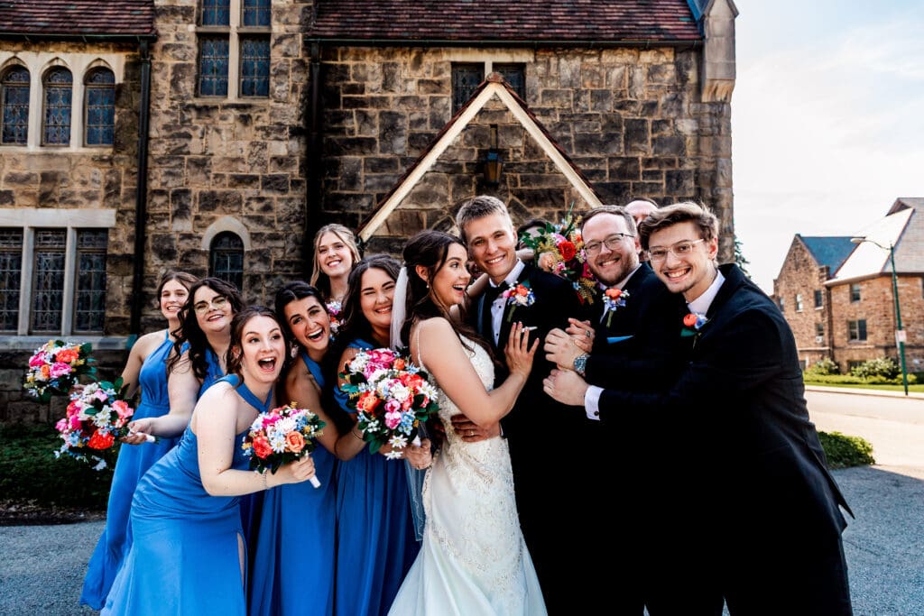 Wedding party poses against a stone wall at Willowbrook