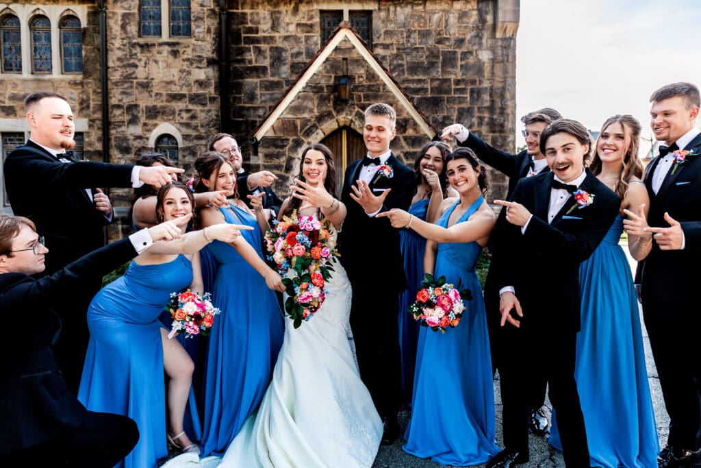 Wedding party laughs together in front of a stone building at Willowbrook