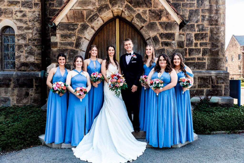 Wedding couple poses with bridesmaids in blue dresses at a Willowbrook wedding