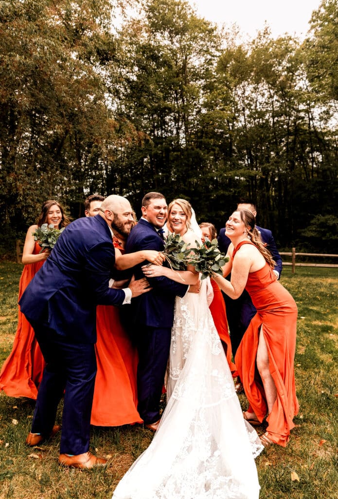 Bridal party sneaking up to hug the newlyweds during wedding portraits at The Barn at Ever Thine in Butler County, PA