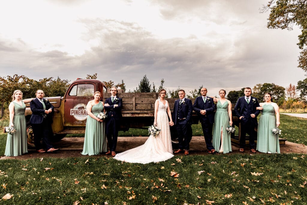 Wedding party arranged in pairs in front of Pinehall truck with bride and groom in the center