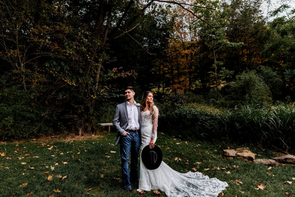 Wedding couple posing with cowboy hat framed by fall foliage at Hinckston Run Farm