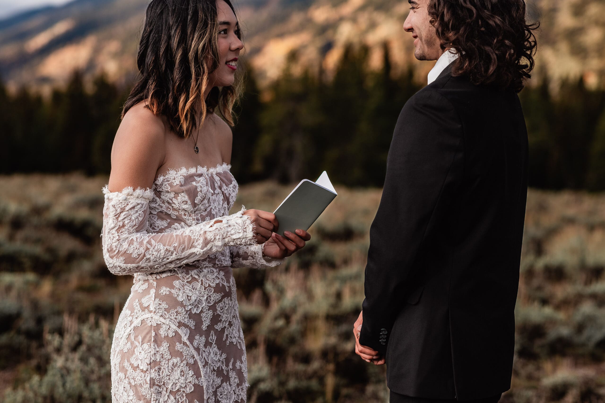 Eloping couple reading their vows to each other in front of the dramatic Teton peaks during their intimate Grand Teton National Park elopement.
