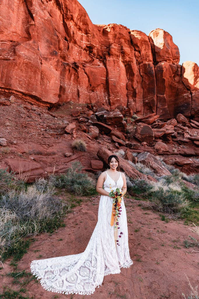 Bride standing for a portrait surrounded by towering canyon walls during an adventurous Moab desert elopement.