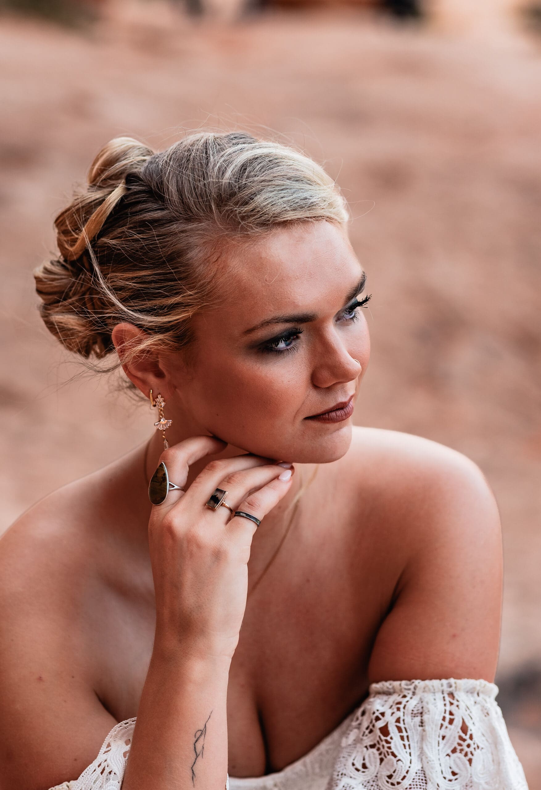 Close-up of the bride’s hair, makeup, and jewelry as she looks off into the distance during her Corona Arch elopement near Moab.