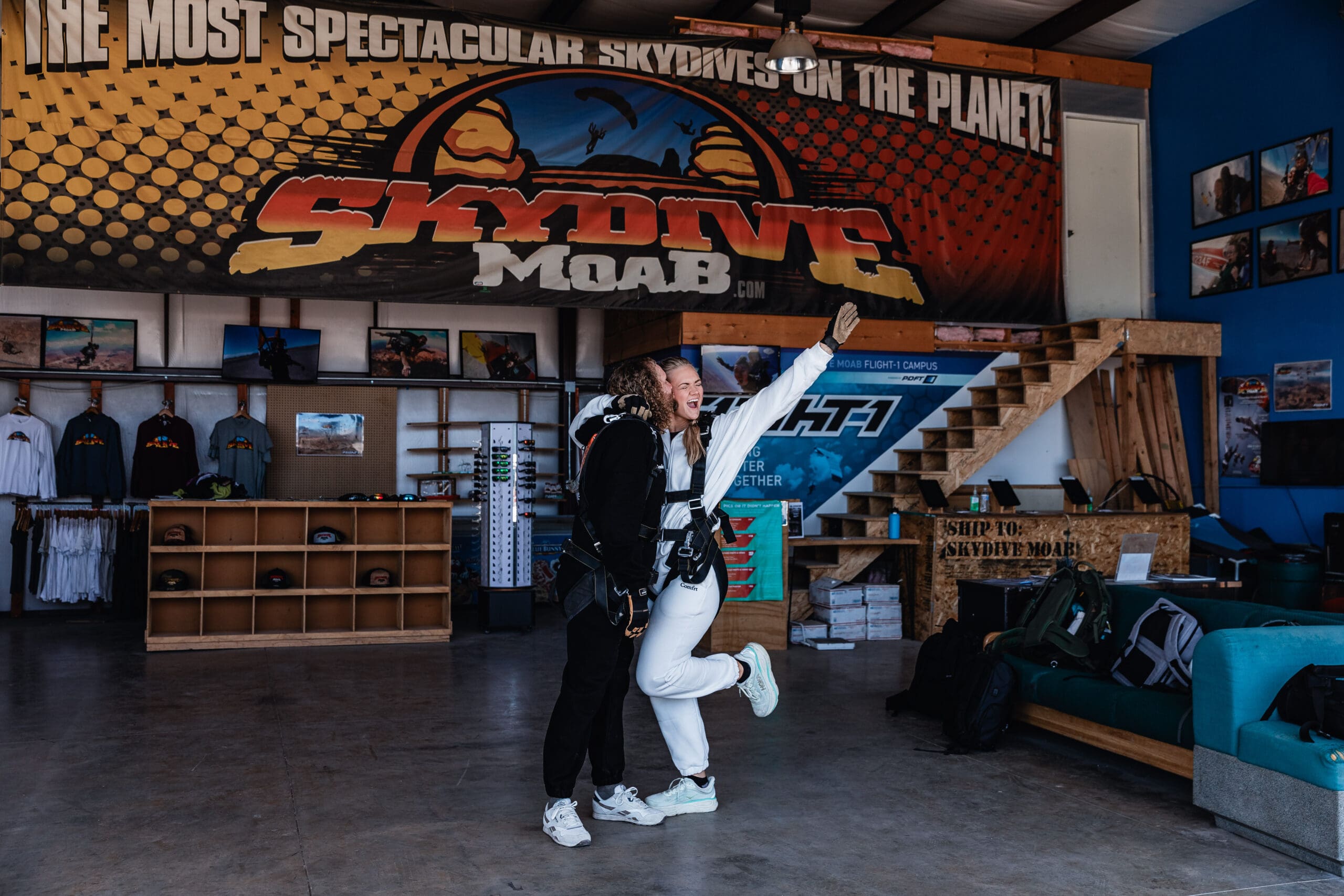 Elopement couple celebrating in front of the Skydive Moab sign before their skydiving adventure in Moab, Utah